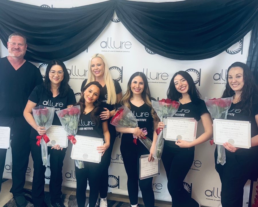 A group in black shirts holding certificates and red roses in front of a white backdrop