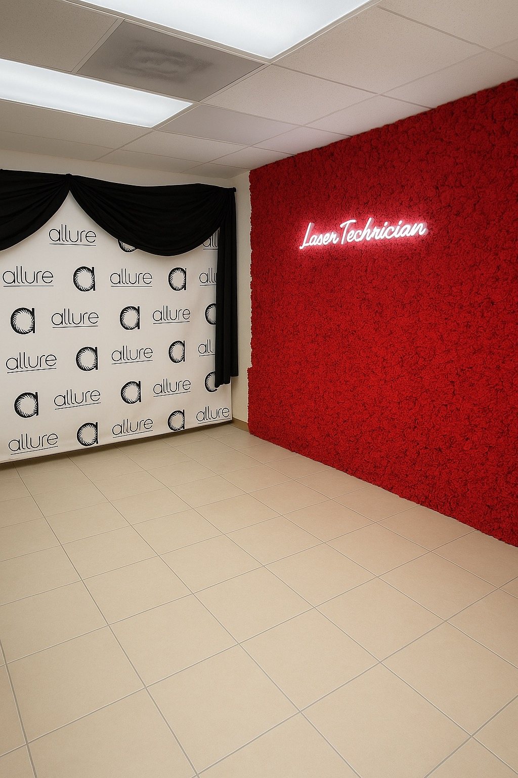 An empty tiled studio with a red flower wall, a neon Laser Technician sign and a black-draped white backdrop